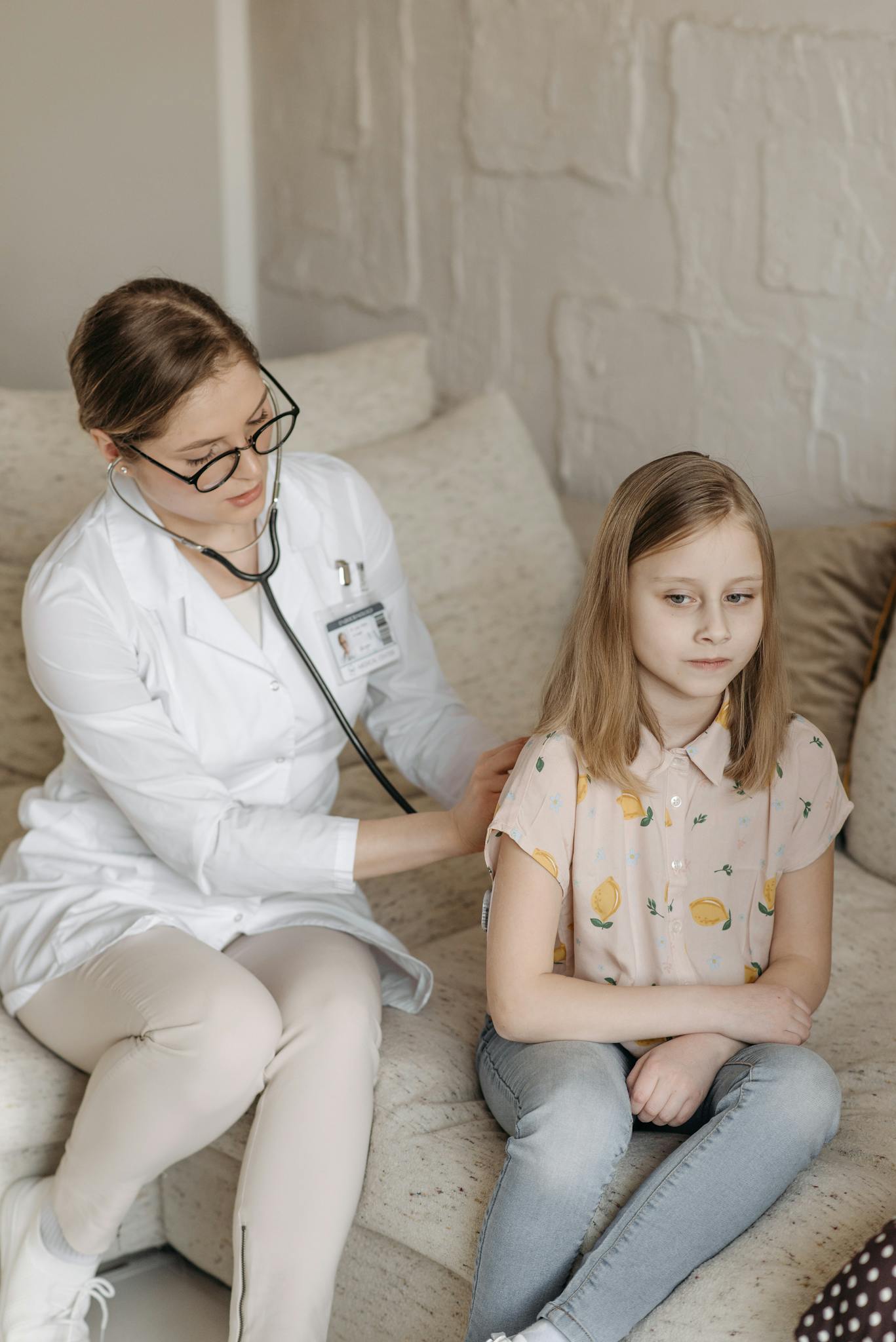 A doctor conducts a health checkup for a young girl at home, ensuring comfort and care.